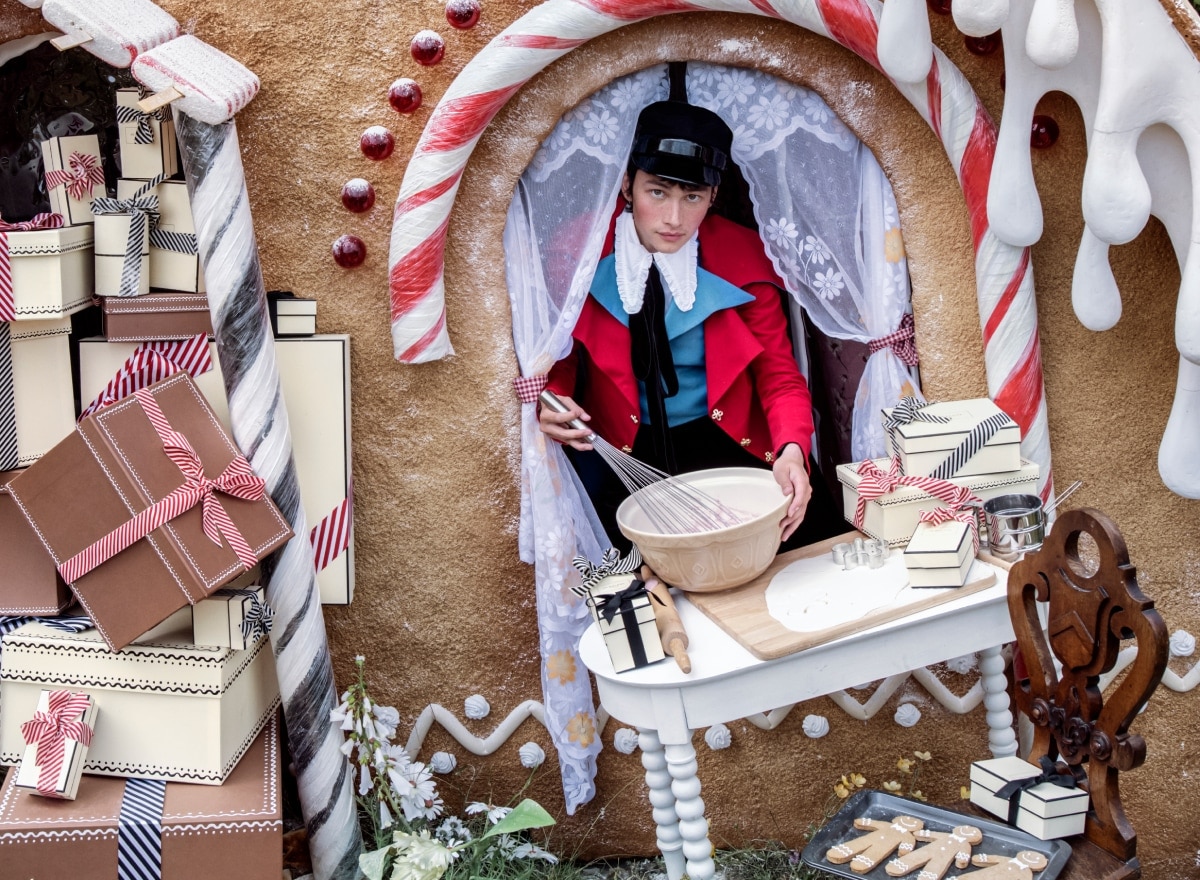 Man with presents in front of a gingerbread house